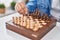 Young arab man playing chess sitting on table at home