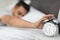 Young Arab Man Reaching Alarm Clock On Bedside Table With Hand