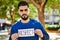 Young arab man serious holding respect banner at park