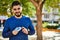 Young arab man smiling confident holding glucometer at park