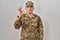 Young arab man wearing camouflage army uniform smiling positive doing ok sign with hand and fingers