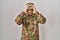 Young arab man wearing camouflage army uniform suffering from headache desperate and stressed because pain and migraine
