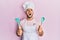 Young arab man wearing professional cook apron and hat holding spoon angry and mad screaming frustrated and furious, shouting with