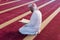 Young Arabic Muslim man reading Koran and praying. Religious muslim man reading holy koran inside the mosque