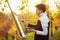 Young artist drawing a picture on canvas on an easel in nature, a man with a brush and a painter gamut among autumn trees, a