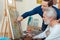 Young artist helping elderly man in painting