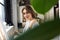 Young artistic girl looking at camera through leaves while painting