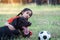 A young Asain girl playing football with her big black dog outside the grass ground in the yard in the evening