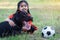 A young Asain girl playing football with her big black dog outside the grass ground in the yard in the evening