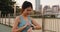 Young Asia athlete lady exercises checking progress looking heart rate monitor on smartwatch in urban city.