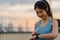 Young Asia athlete lady exercises checking progress looking heart rate monitor on smartwatch in urban city. Teen girl runner