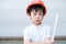 Young Asia boy in gray T shirt wearing a orange safety helmet and holding triangular reduction scales in the garden at home