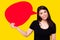 Young Asia woman holding red speech bubble on yellow background. Asian female show sign speech bubble banner, pretty girl get