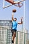 Young asian adult man dunking basketball