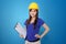 Young Asian architect woman in yellow hard hat, on vibrant blue background