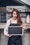 Young asian barista wear jean apron holding blank blackboard coffee menu at counter bar with smile face,cafe service concept,