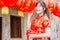 Young asian beautiful girl in chinese traditional red dress smile stand near china lamp, in the Chinese New Year. Festivities.