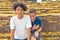 Young Asian brothers smiling under a yellow Handroanthus chrysanthus tree in full bloom