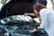 Young asian businesswoman checks the car`s engine oil by herself