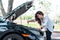 Young asian businesswoman checks the car`s engine oil by herself