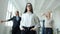 Young Asian businesswoman with serious face standing in office where people men and women dancing