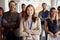 Young asian businesswoman, standing in front of her team. arms crossed, smiling, looking at camera, eye contact. bold and outgoing