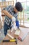 Young asian carpenter drilling wooden job with electric drill