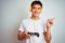 Young asian chinese gamer man playing video game standing over isolated white background very happy pointing with hand and finger