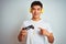 Young asian chinese gamer man playing video game standing over isolated white background very happy pointing with hand and finger