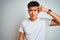 Young asian chinese man wearing t-shirt standing over isolated white background pointing unhappy to pimple on forehead, ugly