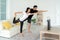 Young Asian couple doing yoga practice together and looking TV at home, man and woman working out together standing in living room