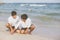 Young asian couple gay smiling romantic drawing heart shape together on sand in vacation