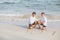 Young asian couple gay smiling romantic drawing word text love together on sand in vacation