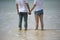 Young asian couple hold hand together stand on beach look to the
