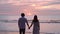 Young Asian couple holding hand together and looking beautiful sunset on the beach, Summer vacation concept