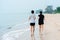 A young Asian couple, jogging comfortably by the sea, and the cool sea waves crashing against their feet,