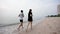 A young Asian couple, jogging comfortably by the sea, and the cool sea waves crashing against their feet, a popular tourist