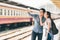 Young Asian couple traveler taking selfie together using smartphone waiting for trip at train station platform in Asia