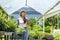 Young Asian customer is choosing exotic plant from the local garden center nursery with shopping cart full of summer plant for