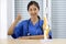 Young asian doctor in blue uniform and stethoscope raise finger thumb up with a smile. An anterior cruciate ligament on deluxe