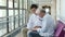 Young asian doctor talking to senior patient in hospital hallway