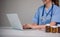 Young Asian doctor in a white medical uniform with a stethoscope using a lab computer and tablet to organize and