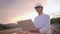 Young asian engineer wear glasses, safety helmet working with portable laptop on outdoor construction land site at sunset