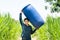 Young Asian farmer carry blue water tank