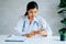 Young Asian female Doctor using a mobile phone at hospital. Healthcare worker scrolling and typing text messages at