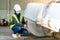 Young Asian female engineer wearing a medical mask to cover her mouth and wearing a white safety helmet Inspecting large floor