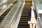 Young Asian female executive going up escalator