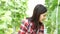 Young Asian female farmer holding a tablet and phone in melon garden field