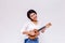 Young Asian female girl playing ukulele beach guitar in white isolated background.