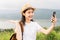 Young Asian female tourist taking video call with friends with beautiful mountain views.